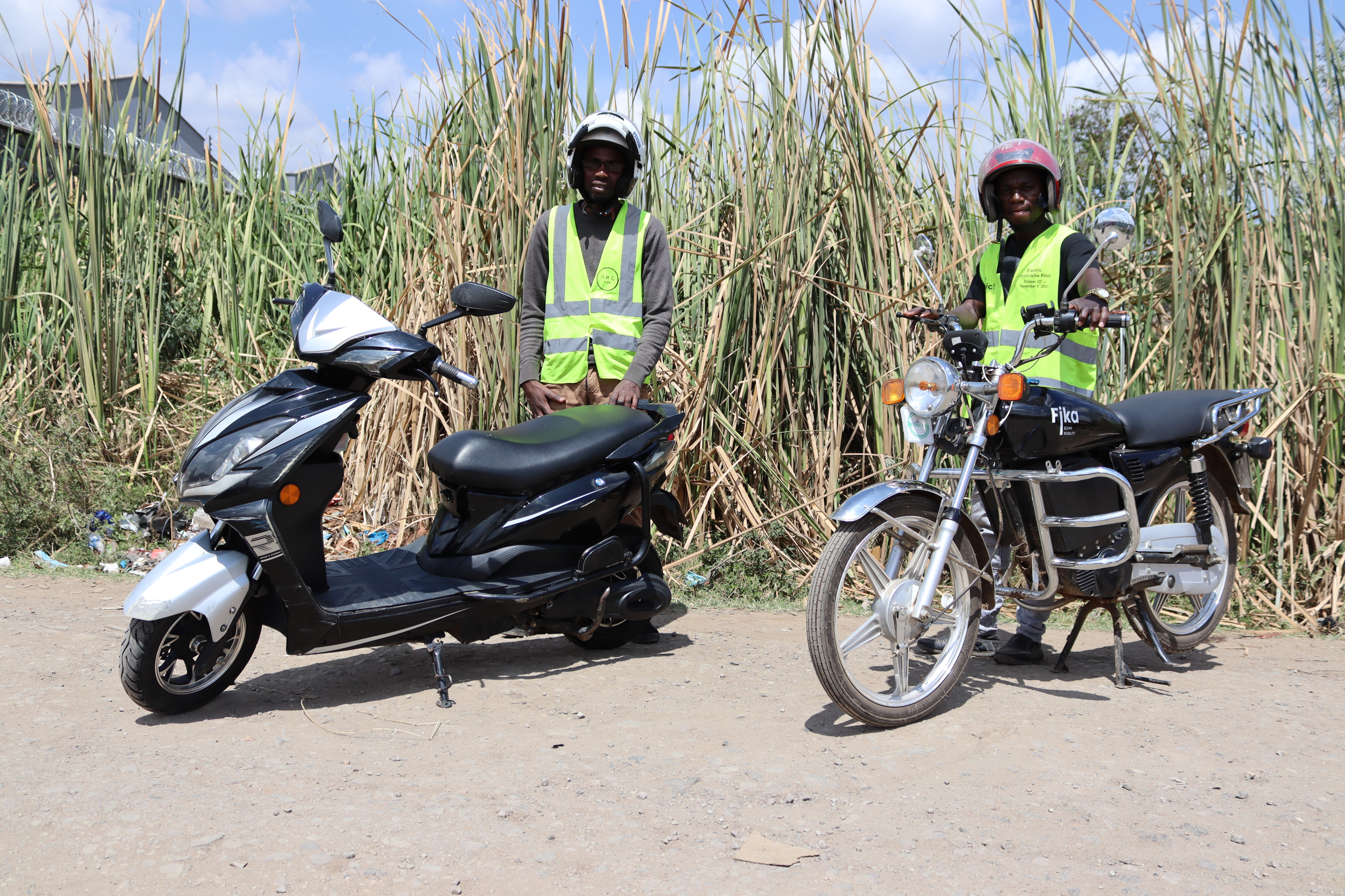 Two men standing next to electric motorcycles