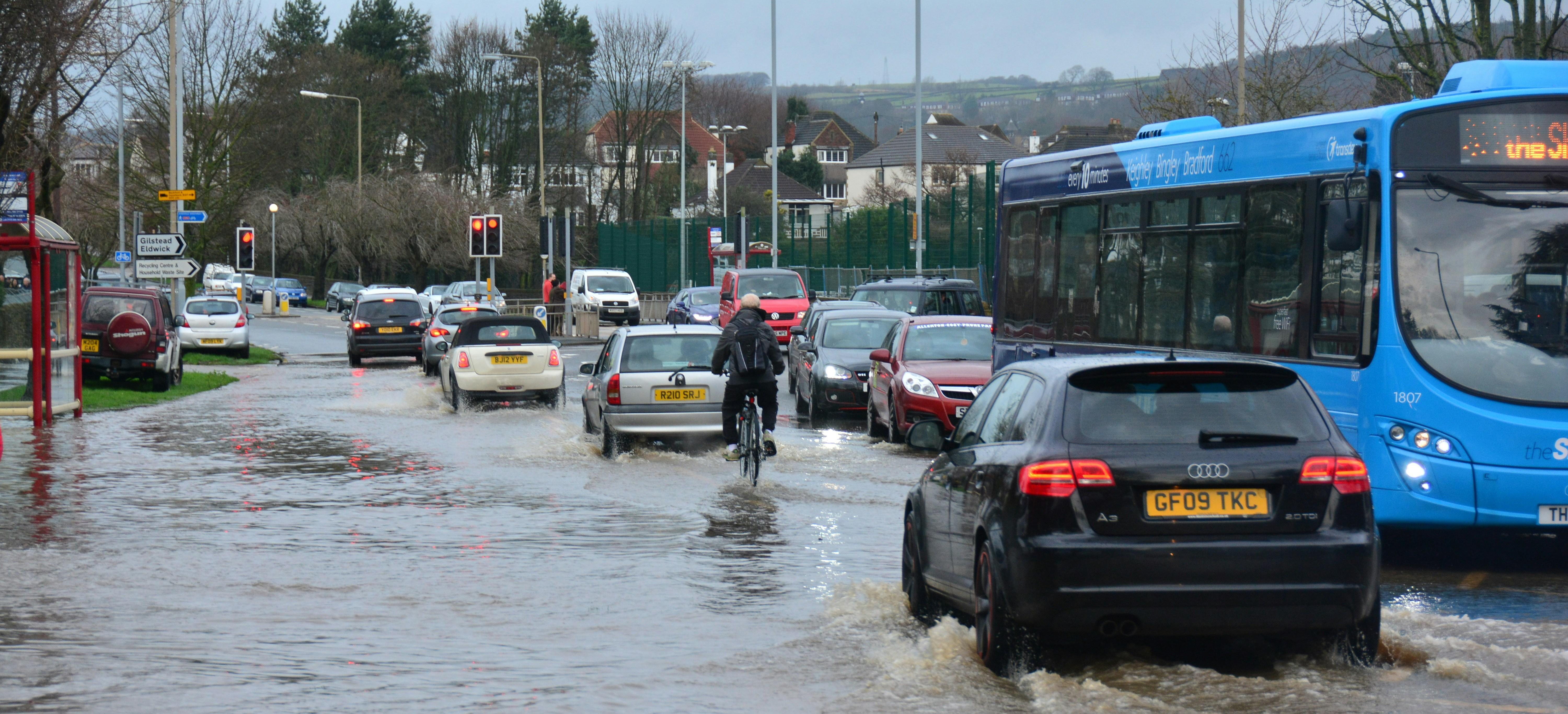 A flooded road in the UK with cars driving through water