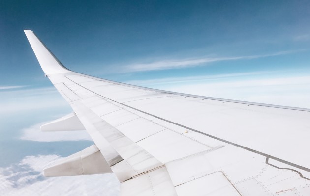 Photo of an aeroplane wing mid-flight, captured as it skims clouds with a blue sky and sea below. Photo by beasty on Unsplash