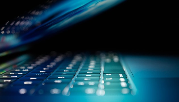 Photo of a laptop opened half-way covered in ominous shadows. Photo by  Philipp Katzenberger on Unsplash