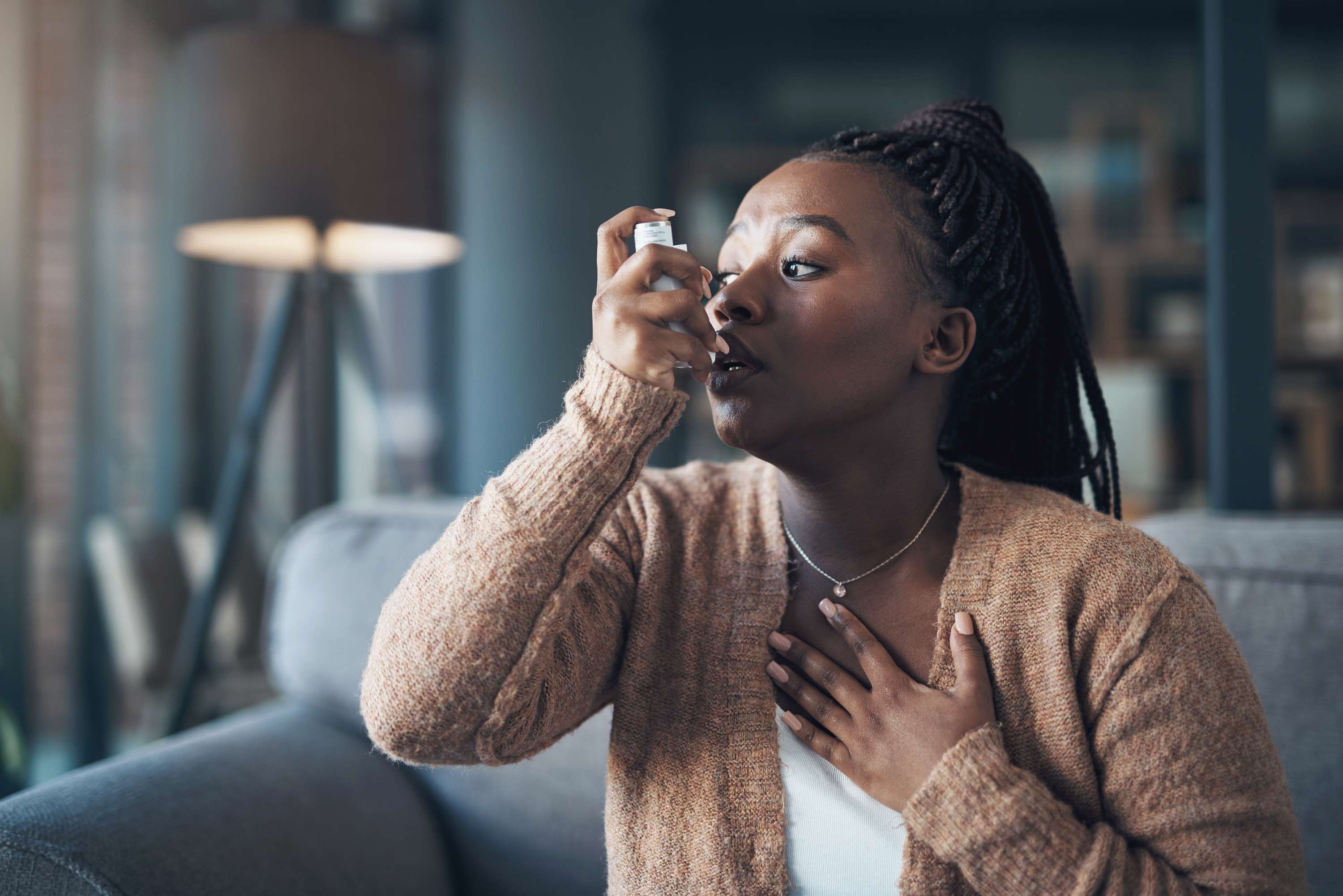 A woman taking a puff from an inhaler