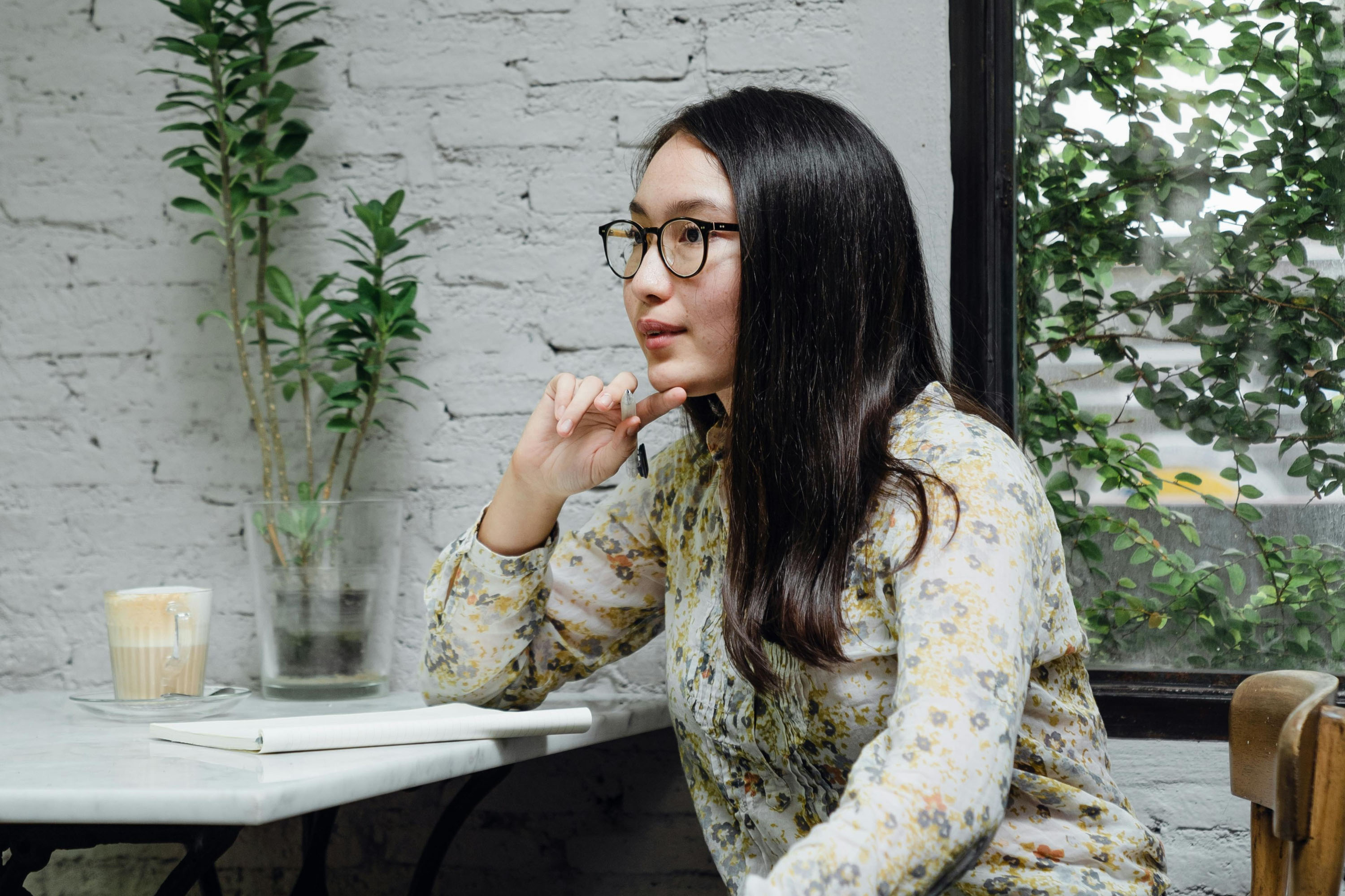 woman with glasses sat at desk with notepad