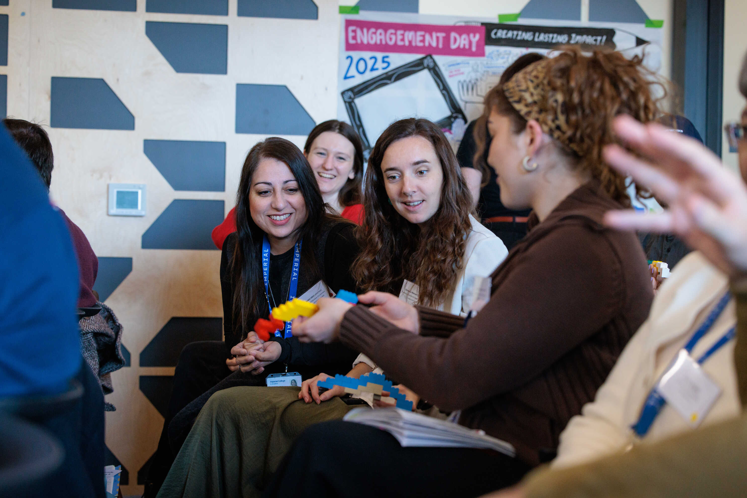 Three delegates discuss the Lego bridge they have built together during the keynote speech.